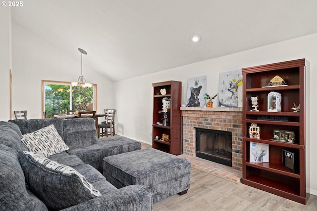 living room with light wood finished floors, a fireplace, vaulted ceiling, a chandelier, and recessed lighting