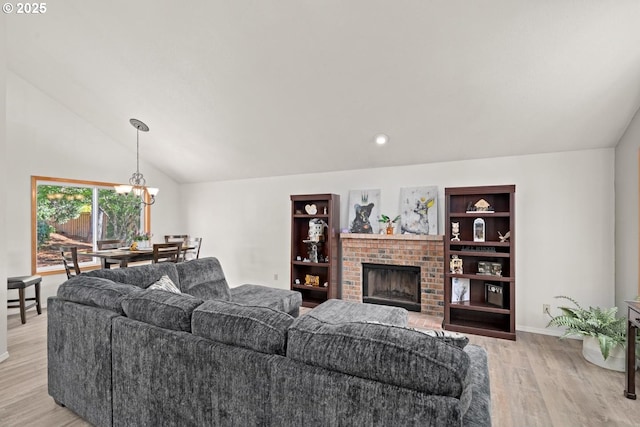 living area with light wood finished floors, a chandelier, a fireplace, lofted ceiling, and baseboards