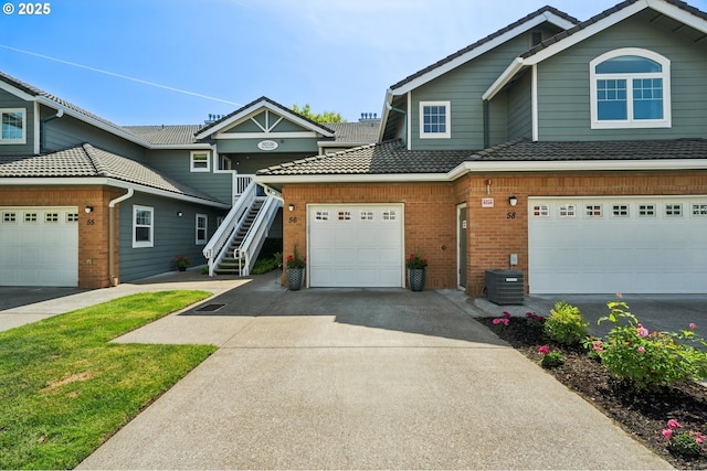 30326 SW Ruth St Unit 56, Wilsonville, OR 97070 - view of front of home featuring driveway, brick siding, stairway, a garage, and central air condition unit