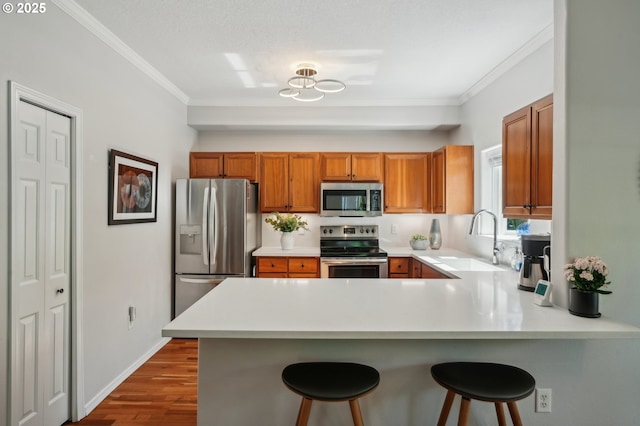 30326 SW Ruth St Unit 56, Wilsonville, OR 97070 - kitchen with stainless steel appliances, brown cabinets, a sink, light countertops, and ornamental molding