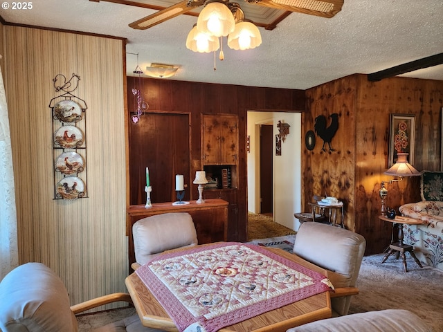 carpeted dining space featuring ceiling fan, wood walls, and a textured ceiling