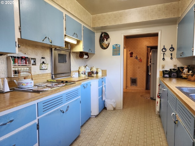 kitchen featuring white fridge, heating unit, blue cabinetry, and butcher block countertops