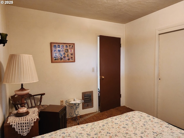 carpeted bedroom with a textured ceiling, a closet, and heating unit