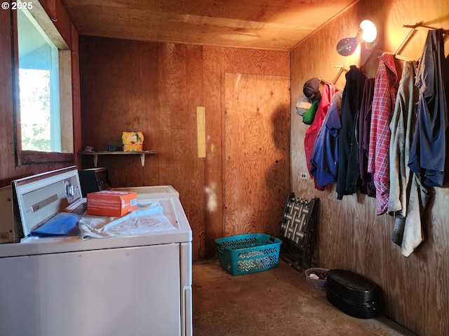 clothes washing area with washing machine and dryer and wooden walls