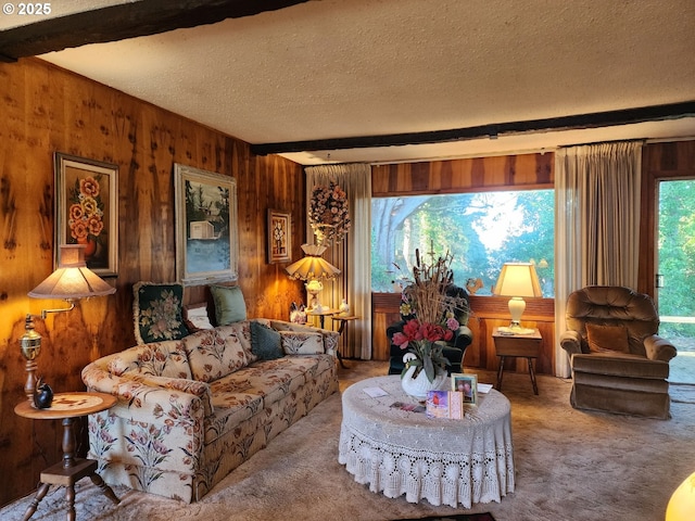 carpeted living room featuring beam ceiling, wood walls, and a textured ceiling