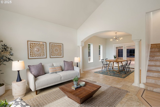 living area with high vaulted ceiling, arched walkways, stairs, stone tile flooring, and baseboards