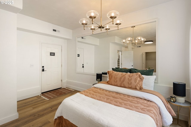 bedroom with a chandelier, wood finished floors, and baseboards