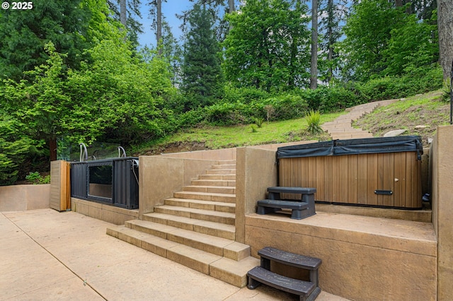 view of patio with a hot tub and stairs