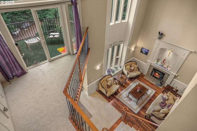 12712 SE 137th Dr, Happy Valley, OR 97086 - carpeted living room featuring a towering ceiling, a decorative wall, a glass covered fireplace, wainscoting, and tile patterned flooring