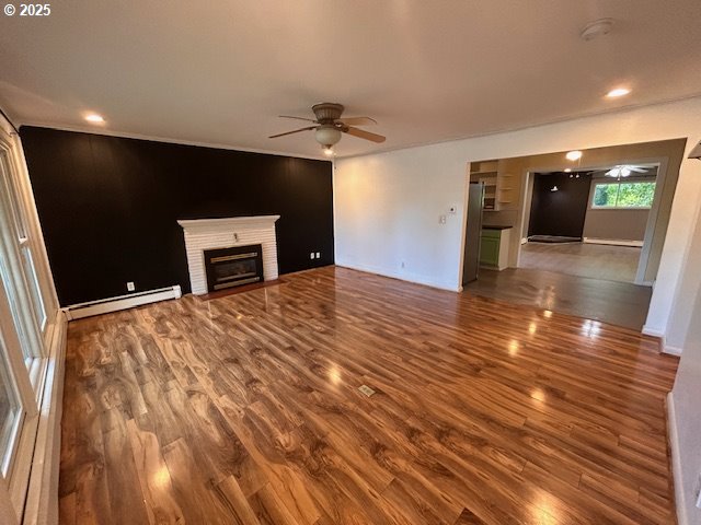 960 E Main St, Hillsboro, OR 97123 - unfurnished living room featuring ceiling fan, baseboard heating, wood finished floors, and a brick fireplace