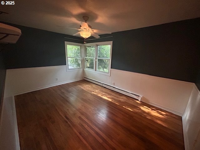960 E Main St, Hillsboro, OR 97123 - empty room featuring baseboard heating, wainscoting, wood finished floors, ceiling fan, and an AC wall unit