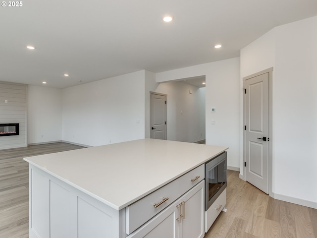 360 NW 29th Way, Battle Ground, WA 98604 - kitchen featuring stainless steel microwave, light wood-type flooring, recessed lighting, a center island, and white cabinets