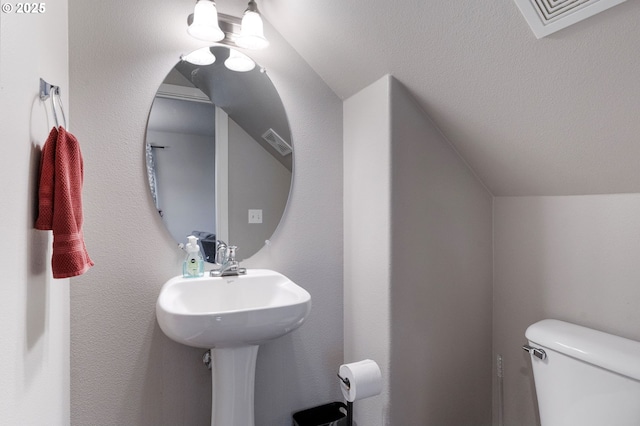 half bath with vaulted ceiling, visible vents, and toilet