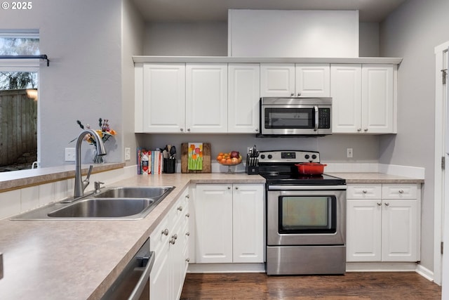 kitchen featuring dark wood-style floors, light countertops, a sink, appliances with stainless steel finishes, and white cabinetry