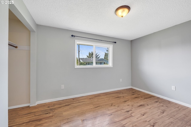 unfurnished bedroom featuring baseboards, wood finished floors, a textured ceiling, and a closet