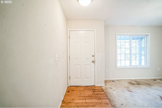 foyer entrance with light hardwood / wood-style floors and a textured ceiling