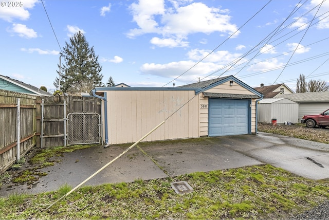 detached garage featuring concrete driveway, fence, and a gate