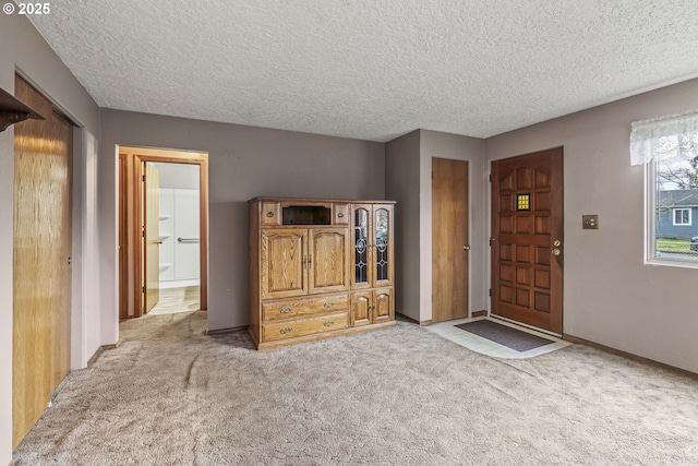 entryway featuring light colored carpet, a textured ceiling, and baseboards