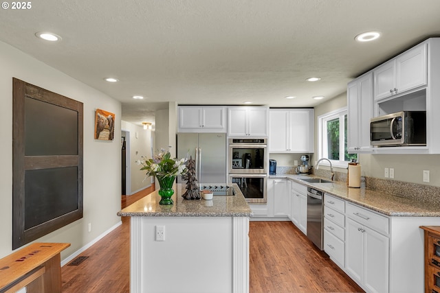 4249 SE 18th Ct, Gresham, OR 97080 - kitchen with appliances with stainless steel finishes, a center island, white cabinetry, light wood-type flooring, and light stone countertops