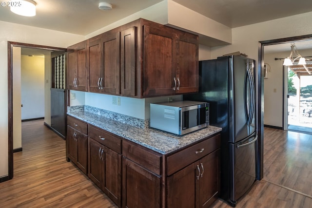 5310 Green Valley Rd, Oakland, OR 97462 - kitchen featuring stainless steel microwave, wood finished floors, light stone counters, dark brown cabinets, and baseboards