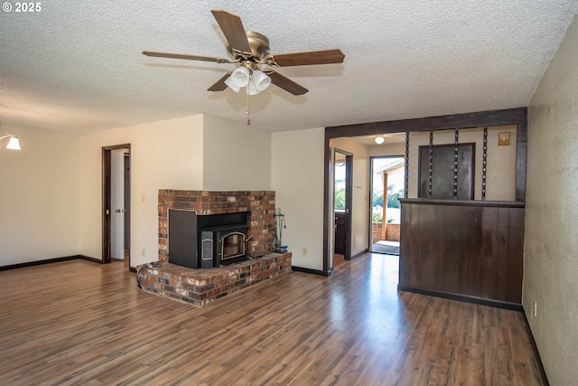 5310 Green Valley Rd, Oakland, OR 97462 - unfurnished living room with a textured ceiling, wood finished floors, baseboards, a ceiling fan, and a wood stove