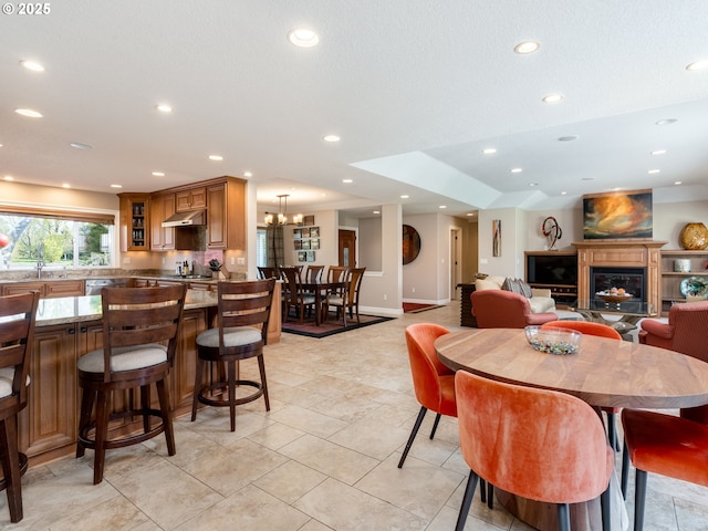 dining space with an inviting chandelier, a glass covered fireplace, baseboards, recessed lighting, and light tile patterned floors