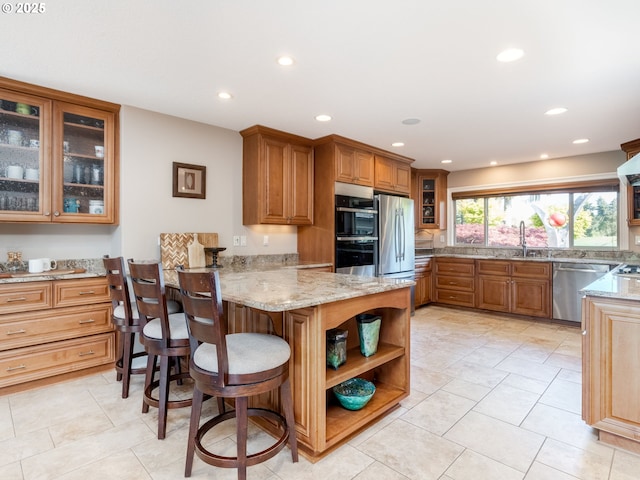 kitchen with brown cabinets, stainless steel appliances, light stone countertops, and a peninsula