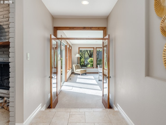 interior space with carpet flooring, a fireplace, tile patterned floors, french doors, and baseboards