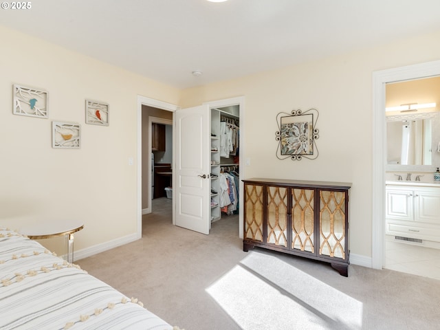 bedroom with visible vents, a sink, a closet, a spacious closet, and light carpet