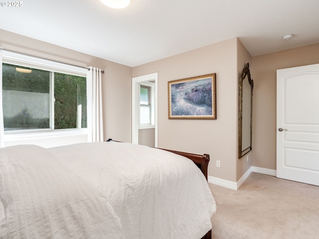 bedroom with baseboards and light colored carpet