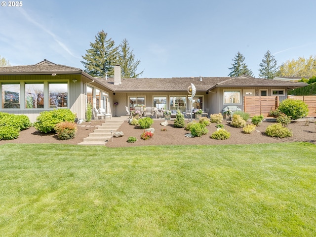 back of house featuring a lawn, board and batten siding, a patio area, and a chimney
