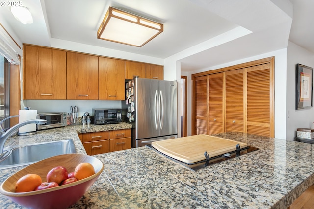 kitchen featuring stainless steel refrigerator, kitchen peninsula, and sink