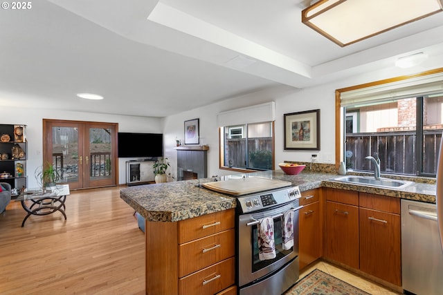 kitchen featuring sink, light hardwood / wood-style flooring, appliances with stainless steel finishes, french doors, and kitchen peninsula