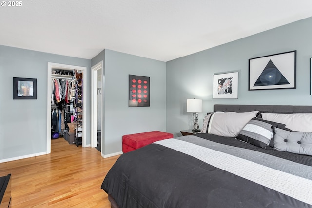 bedroom with a walk in closet, light hardwood / wood-style flooring, and a closet