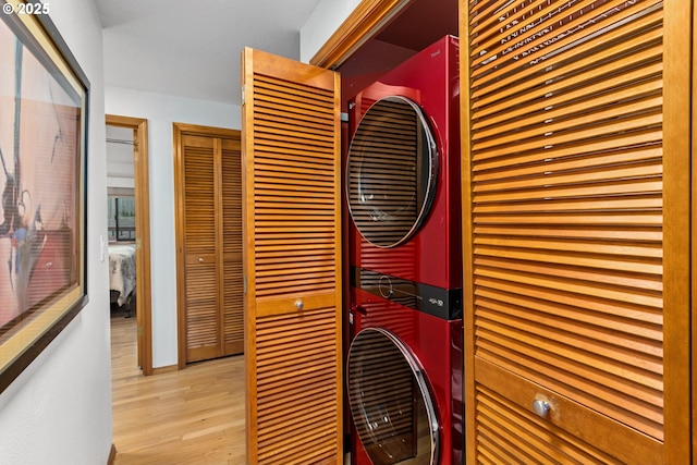 laundry area featuring stacked washer and dryer and light hardwood / wood-style flooring