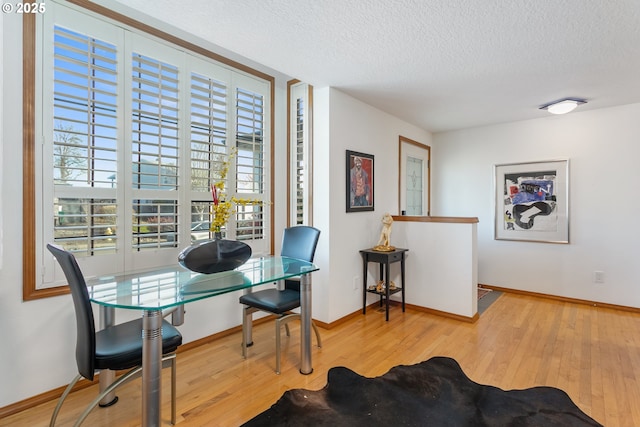 dining room with light hardwood / wood-style flooring and a textured ceiling