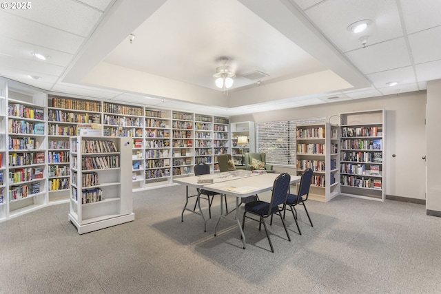 carpeted dining room with ceiling fan and a tray ceiling