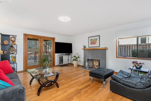 living room featuring a tiled fireplace and light hardwood / wood-style flooring