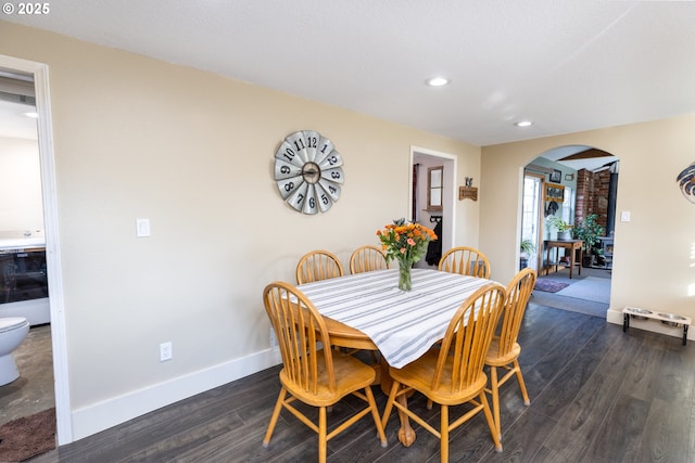 dining room with arched walkways, recessed lighting, dark wood finished floors, and baseboards