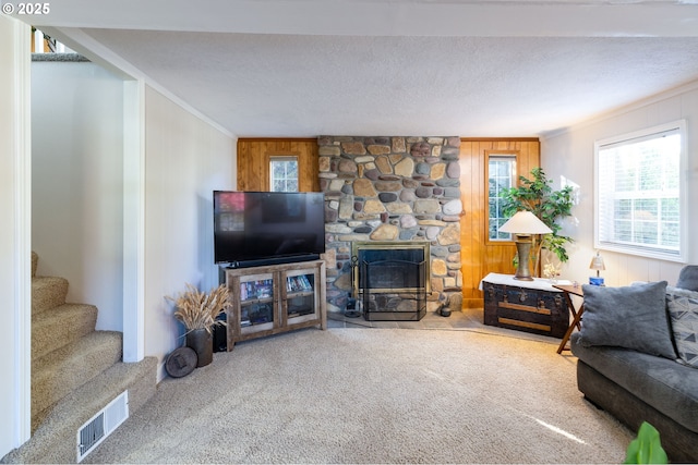 living area featuring a textured ceiling, visible vents, stairs, ornamental molding, and carpet