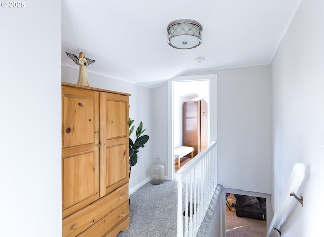 hallway with lofted ceiling, ornamental molding, carpet, and baseboards