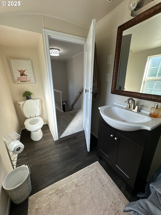 bathroom featuring toilet, baseboards, wood finished floors, and vanity