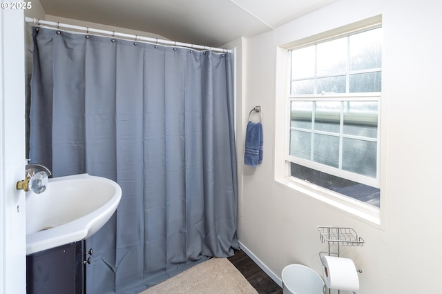 bathroom featuring curtained shower, baseboards, and wood finished floors