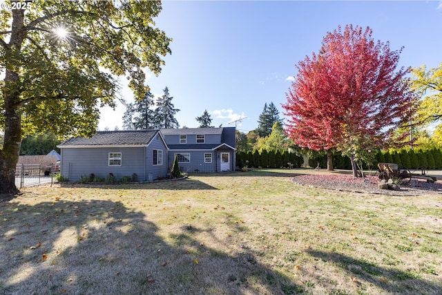 rear view of house featuring a yard and fence