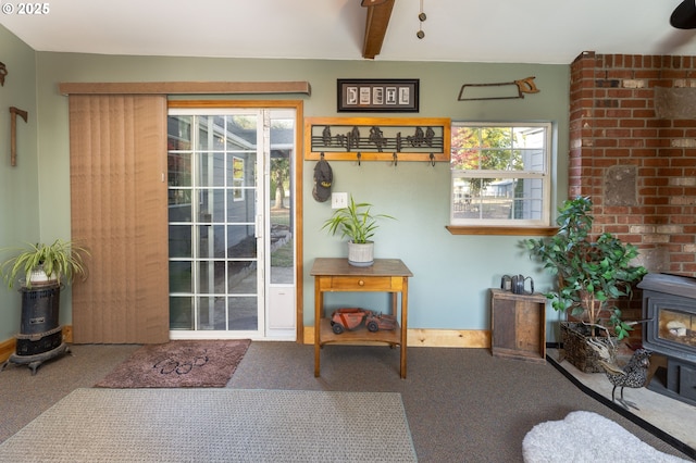 doorway to outside featuring a wood stove, carpet flooring, and beam ceiling