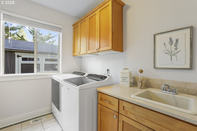 clothes washing area with cabinet space, light tile patterned floors, visible vents, washer and dryer, and a sink