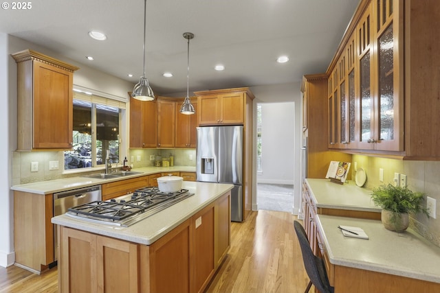 kitchen with a kitchen island, hanging light fixtures, a sink, stainless steel appliances, and backsplash