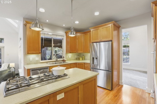 kitchen featuring light countertops, appliances with stainless steel finishes, a sink, and a wealth of natural light