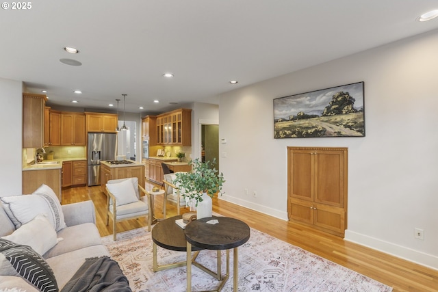 living area featuring baseboards, recessed lighting, and light wood-style floors