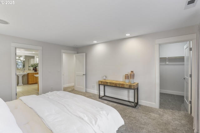 bedroom with visible vents, light carpet, a spacious closet, and baseboards